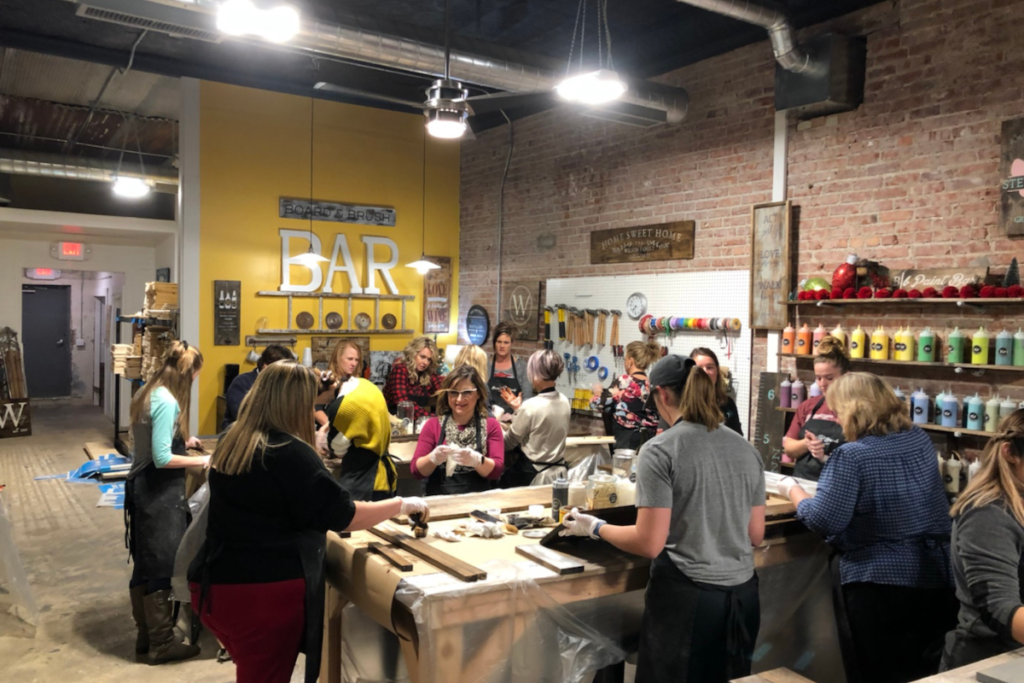 people at a board and brush studio making wood art